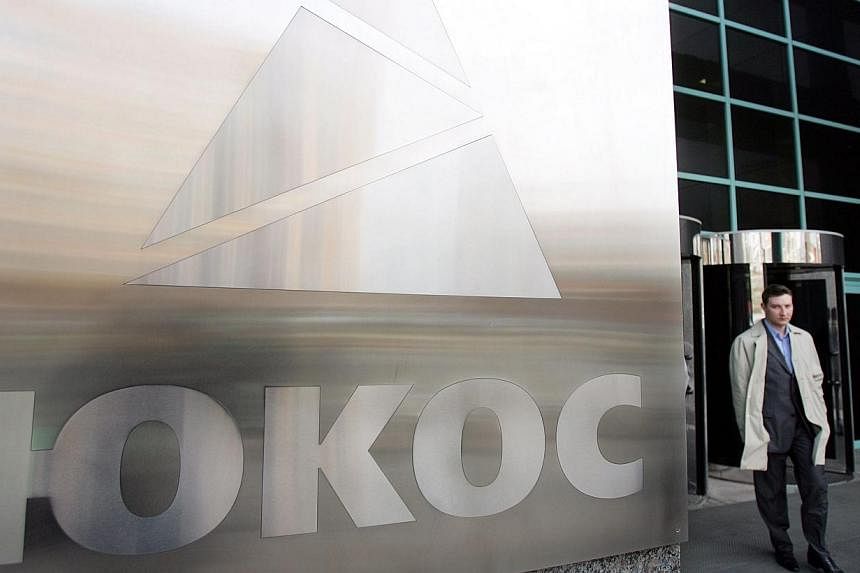 A file photo taken on April 4, 2007 shows a man walking next to the logo of oil giant Yukos at the Moscow headquarters.&nbsp;An international court ordered Russia on Monday to pay Yukos shareholders a record US$50 billion (S$62 billion) compensation 