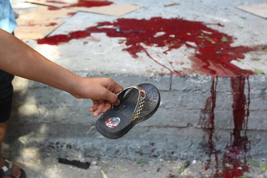 A Palestinian man shows the slipper of a chid as blood is seen on the ground at the scene of an explosion at a public garden in Gaza City on July 28, 2014.&nbsp;Bloodshed in and around Gaza surged on Monday with a strike killing eight Palestinian chi