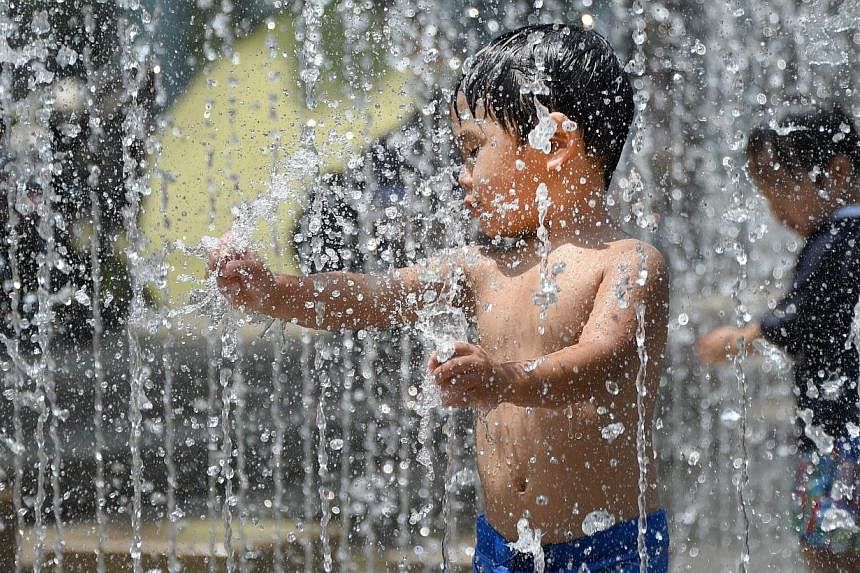 Children enjoy bathing in the fountain at a park in Tokyo on July 26, 2014.&nbsp;Sweltering summer heat in Japan has left at least 15 people dead over the past week, while more than 8,000 others were rushed to hospital with heatstroke symptoms, offic