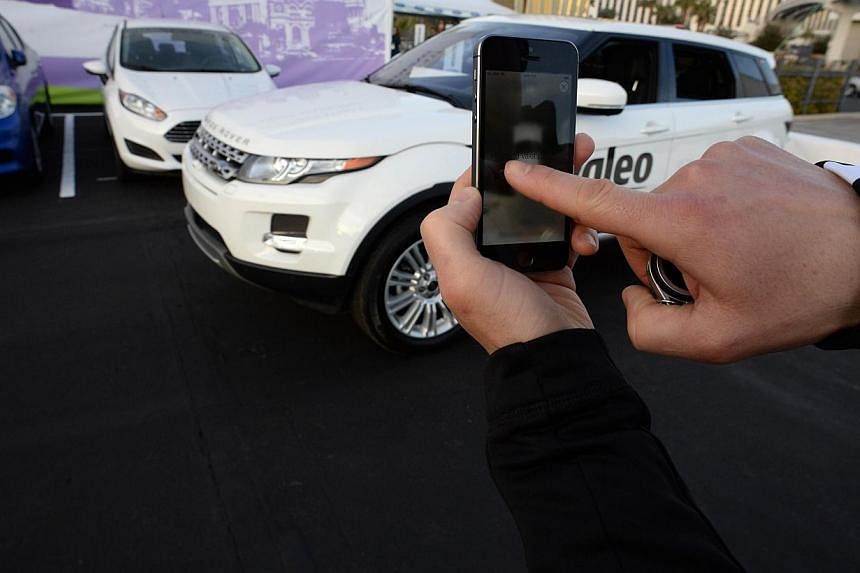 A file photo taken on January 8, 2014 shows a Valeo representative swiping his finger across an iPhone to initiate a self-parking demonstration during a driverless car demo at the 2014 International CES in Las Vegas, Nevada.&nbsp;Driverless cars will
