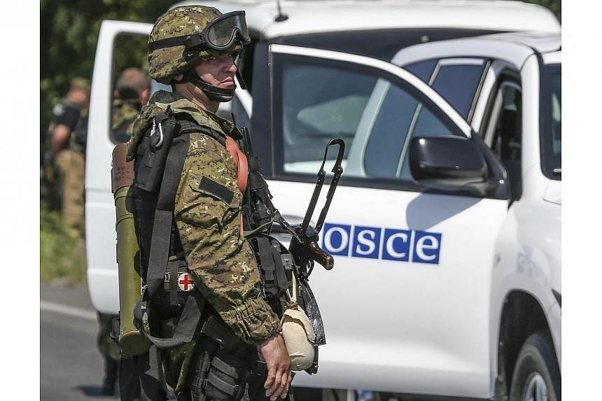 An armed pro-Russian separatist looks back next to a vehicle of the Organisation for Security and Cooperation in Europe's (OSCE) monitoring mission in Ukraine, on the way to the site in eastern Ukraine where the downed Malaysia Airlines flight MH17 c