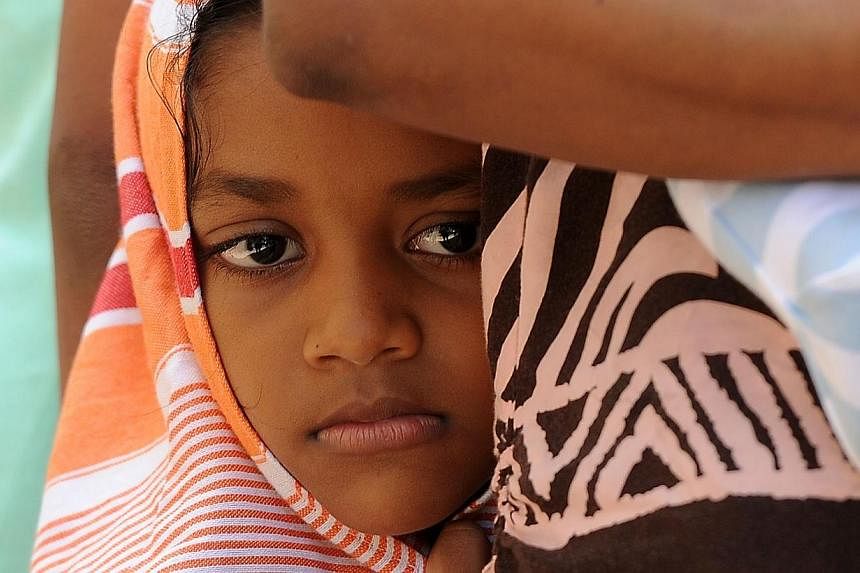 A child among a group of Sri Lankan asylum seekers sent back by Australia looks on before entering the magistrate's court in the southern port district of Galle on July 8, 2014.&nbsp;-- PHOTO: AFP