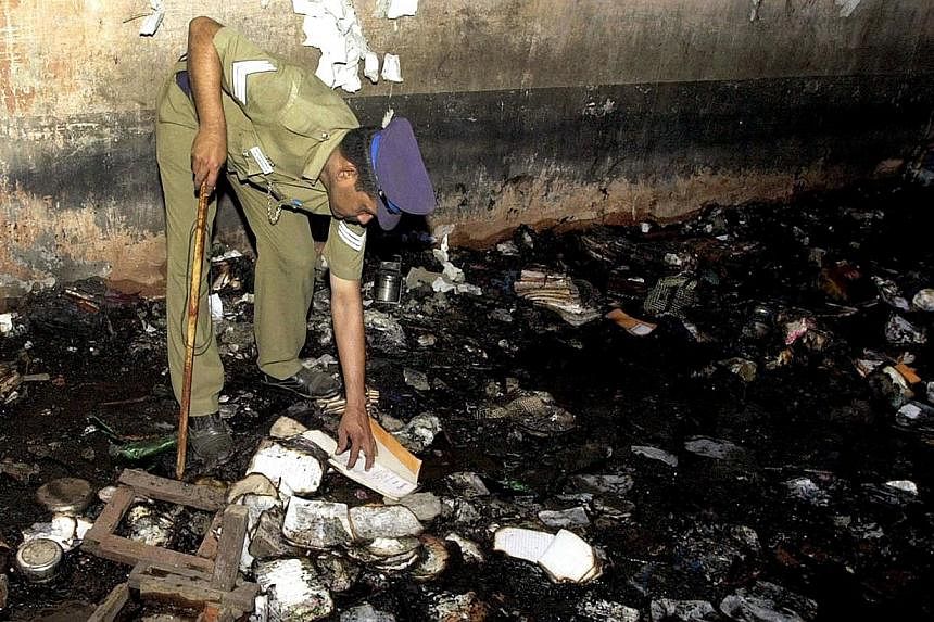 An Indian police officer picks through debris after a fire in a school building in the town of Kumbokonam some 350kms southwest of Chennai on July 16, 2004. -- PHOTO: AFP