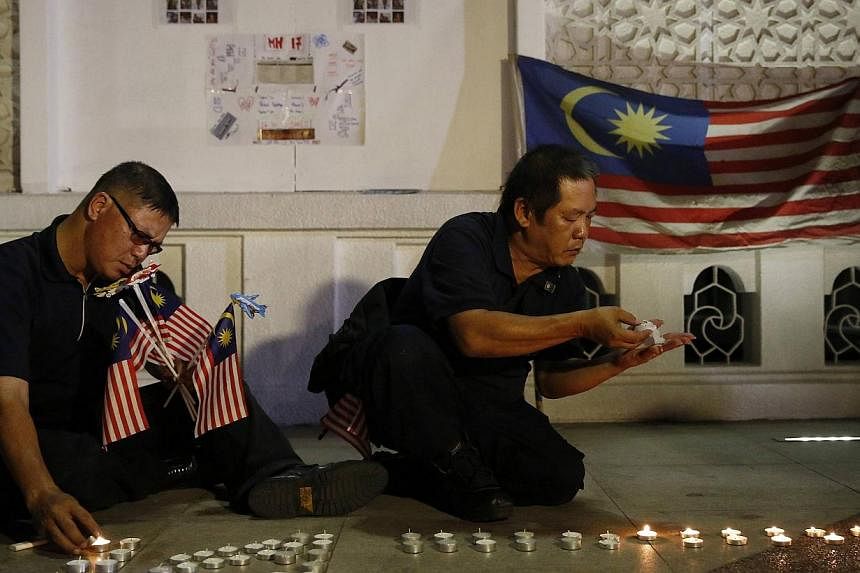Men light candles at a vigil for victims of Malaysia Airlines Flight MH17 in Kuala Lumpur on July 22, 2014.&nbsp;Families of passengers and crew of the missing Malaysia Airlines (MAS) flight MH370 have offered their help to counsel to the families of