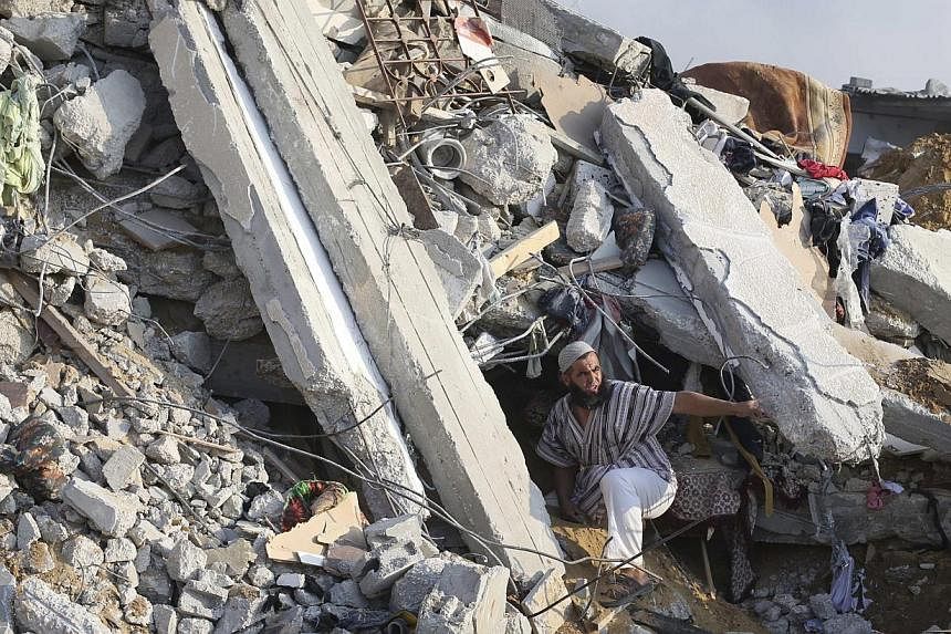 A Palestinian man searches for victims under the rubble of a house, which witnesses said was destroyed in an Israeli air strike, in Rafah in the southern Gaza Strip on July 29, 2014. -- PHOTO: REUTERS