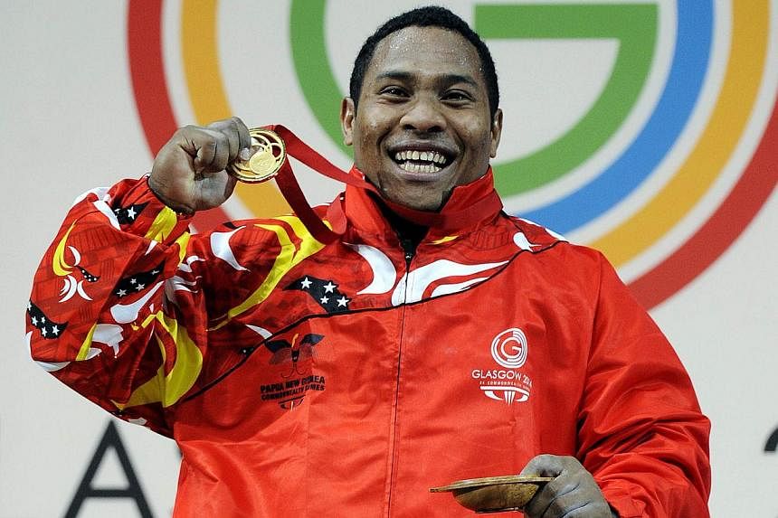 Stephen Kukuna Kari of Papua New Guinea poses for photographs with his gold medal after the men's 94kg weightlifting final at the SECC Precinct during the 2014 Commonwealth Games in Glasgow on July 29, 2014. -- PHOTO: AFP