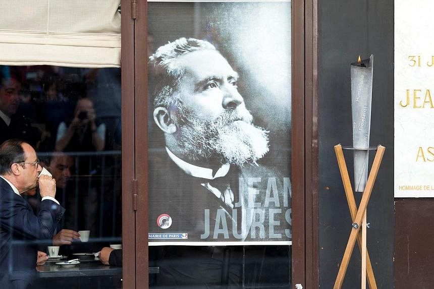 French President Francois Hollande drinks a cup of coffee by a portrait of Jean Jaures on July 31, 2014, inside the Cafe du Croissant after taking part to a commemoration ceremony at the place where French socialist leader and pacifist Jean Jaures wa