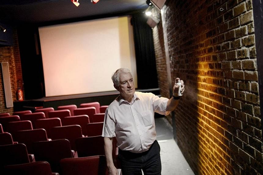 Mr Maurice Laroche, director of the Cinema Le Beverley movie theatre, sprays air freshener in the theatre in Paris on July 15, 2014. -- PHOTO: AFP