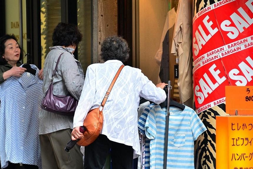 Customers browse shirts at an apparel shop in Tokyo on May 15, 2014.&nbsp;Japan must raise its sales tax again to conquer one of the world's heaviest public debt burdens, the International Monetary Fund (IMF) said on Thursday, July 31, 2014, as it ca