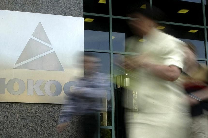 People walk by the Yukos oil company headquarters in Moscow on July 8, 2004.&nbsp;The European Court of Human Rights on Thursday, July 31, 2014, ordered Russia to pay former shareholders in defunct oil giant Yukos almost 1.9 billion euros (S$3.17 bil
