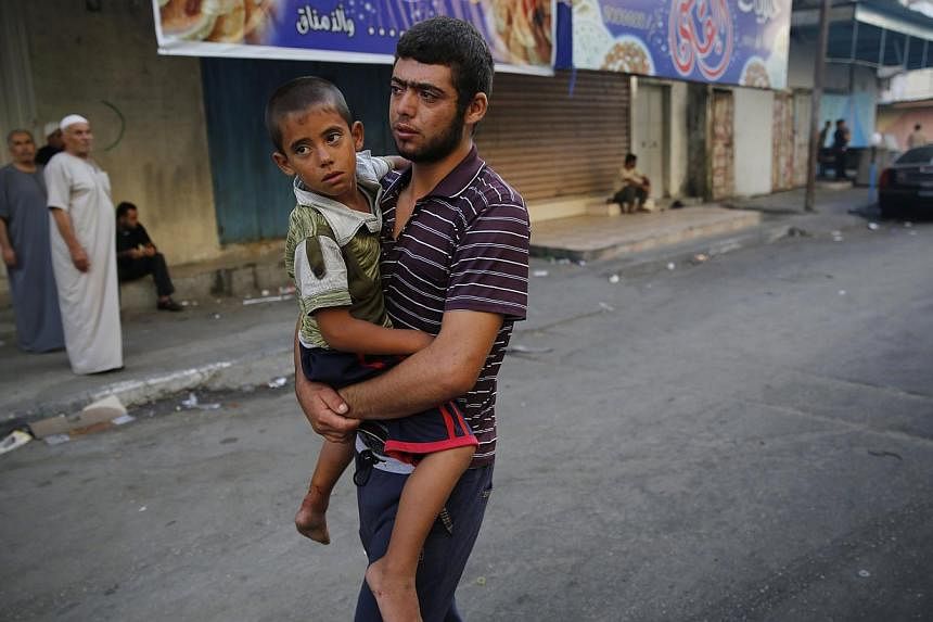 A Palestinian man carrying a child, who was injured by what medics said was Israeli shelling during an Israeli ground offensive, from a hospital in Beit Lahita in the northern Gaza Strip yesterday.