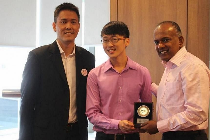 The Bone Marrow Donor Programme's 100th donor Lim Yun Song (centre) receives a token of appreciation from Minister for Law and Foreign Affairs K Shanmugam (right), the programme's new patron, and the organisation's honorary secretary Martin Thoo. -- 