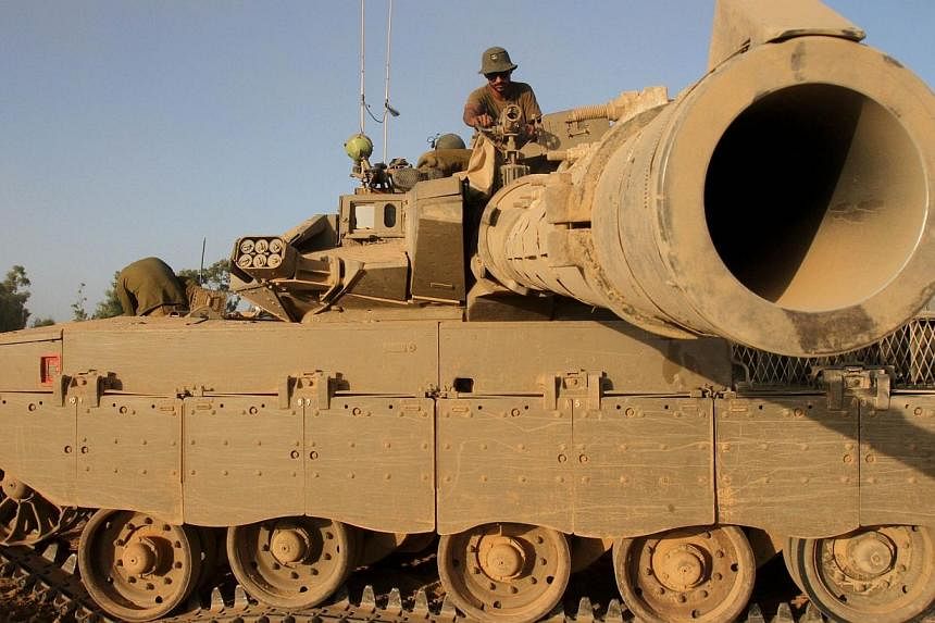 An Israeli soldier sits on top of a Merkava tank along the border between Israel and the Hamas-controlled Gaza Strip, on July 30, 2014, after returning from combat in the Palestinian enclave.&nbsp;-- PHOTO: AFP