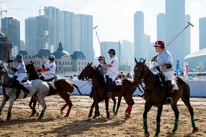 This photo taken on July 5, 2014 shows people playing polo on a field in the city of Dalian in north-east China's Liaoning province. A growing number of the country's wealthy elite are discovering the joys of the saddle and the whip. -- PHOTO: AFP