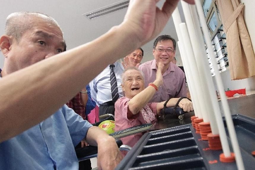 Minister for Health Mr Gan Kim Yong (right) poses for the cameras with Madam Ho Kim Choo (centre), 73, at the physiotherapy room during a tour of the Society for Aged Sick's new tower block on July 31, 2014.&nbsp;-- ST PHOTO: NEO XIAOBIN