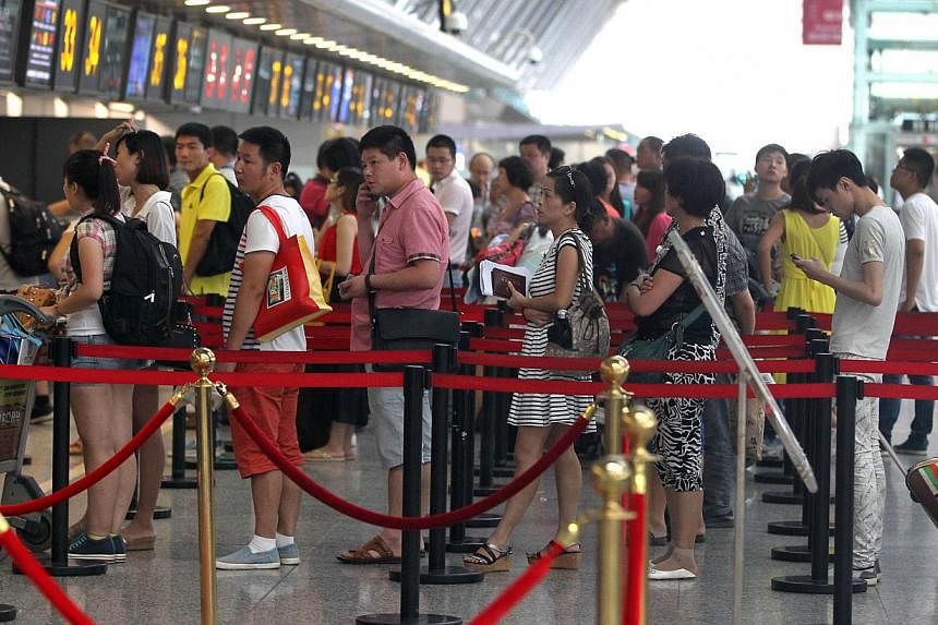 Passengers queue up to check in at Zhengzhou Xinzheng International Airport in Zhengzhou, central China's Henan province on July 29, 2014.&nbsp;China's Defence Ministry on Thursday, July 31 said that military drills in south-east coastal regions were