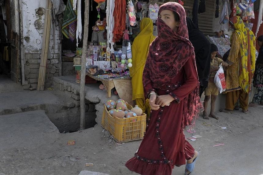 This photograph taken on July 28, 2014, shows a Pakistani female pedestrian as she walks through a market in Quetta in the southwestern Baluchistan province, the site of an acid attack on female pedestrians. -- PHOTO: AFP