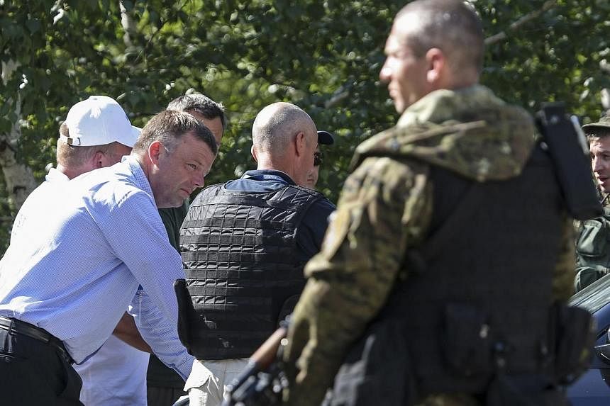 Alexander Hug (left), deputy head for the Organisation for Security and Cooperation in Europe's (OSCE) monitoring mission in Ukraine, looks on next to an armed pro-Russian separatist on the way to the site in eastern Ukraine where the downed Malaysia