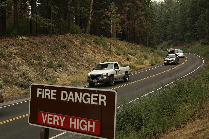 Vehicles are escorted from Yosemite National Park along Highway 120 at the park's entrance in Big Oak Flat, California on July 30, 2014. -- PHOTO: REUTERS