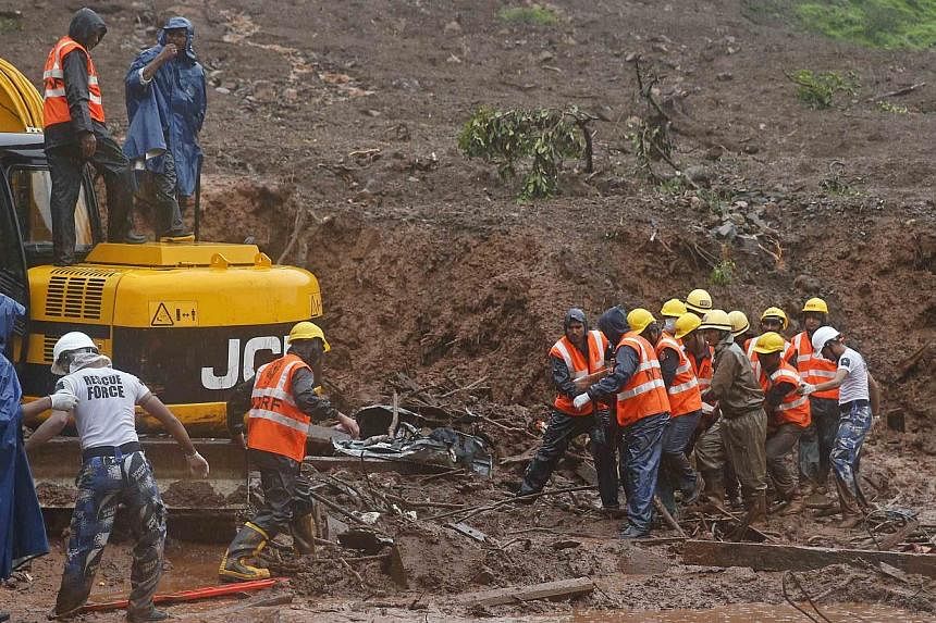 National Disaster Response Force (NDRF) personnel carry the body of a victim from the site of a landslide at Malin village, in the western Indian state of Maharashtra on July 31, 2014. -- PHOTO: REUTERS