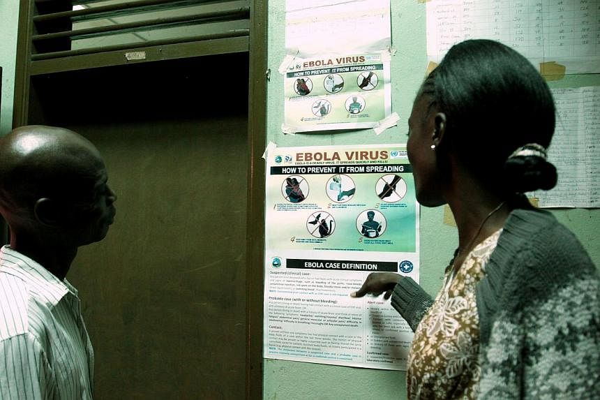 Liberian people read an information sign about Ebola set on a wall of a public health center in Monrovia on July 31, 2014. -- PHOTO: AFP
