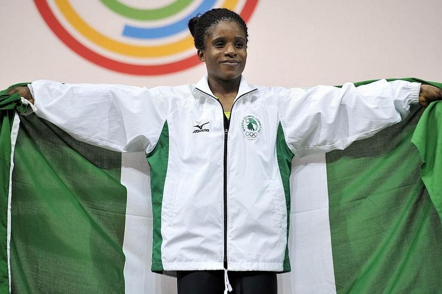 Nigeria's gold medallist Chika Amalaha celebrates on the podium at the medal ceremony for the women's weightlifting 53kg class, at the SECC Precinct during the 2014 Commonwealth Games in Glasgow, Scotland on July 25, 2014.&nbsp;-- PHOTO: AFP