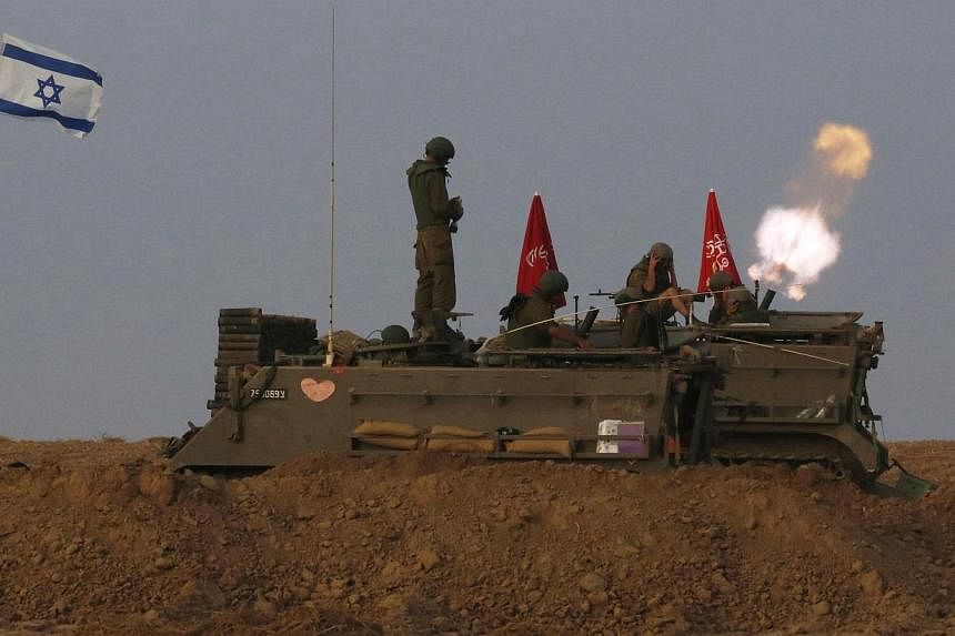 Israeli soldiers stand on an armoured personnel carrier (APC) outside the central Gaza Strip as they fire mortar shell towards Gaza before a ceasefire was due, early on Aug 1, 2014. -- PHOTO: REUTERS