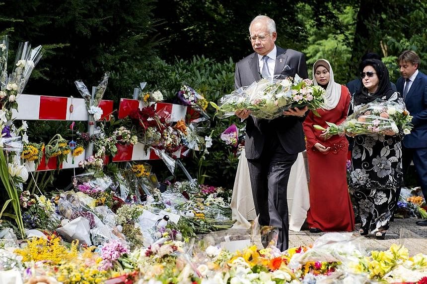 Malaysian Prime Minister Najib Razak and his wife Rosmah Mansor (second, right) lay flowers at the Korporaal van Oudheusdenkazerne in Hilversum, the Netherlands, on July 31, 2014, where the identification process will take place of the victims of the