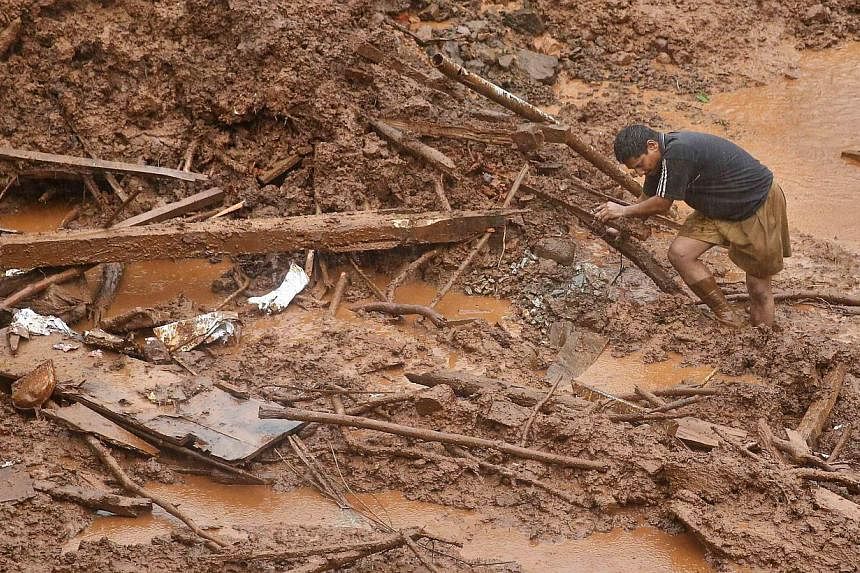 A rescue worker searches for survivors at the site of a landslide at Malin village in the western Indian state of Maharashtra on July 31, 2014. -- PHOTO: REUTERS