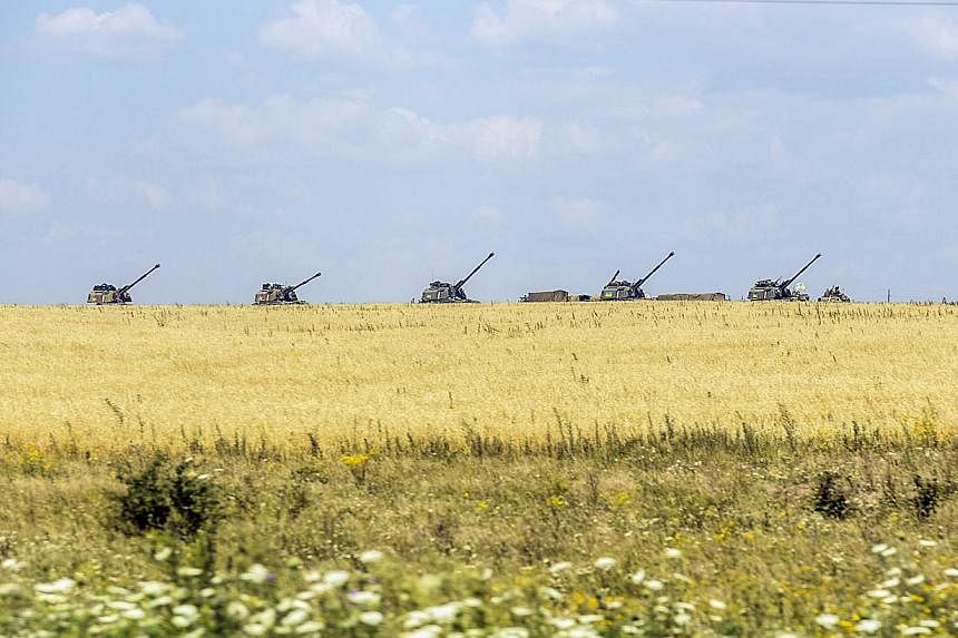 Ukrainian tanks stand guard near a field on July 31, 2014 in the village of Debaltseve, in the Donetsk region, eastern Ukraine.&nbsp;With hazards including blown-up railway bridges and unexploded shells and mines, the route chosen by international in
