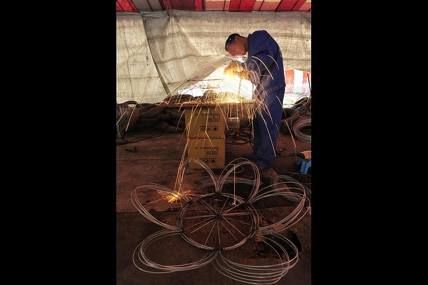 Craftsmen from Sichuan, China, work long hours to complete the flower lanterns, welding raw materials to create a wire frame (above) and leaving the lanterns to air dry after the cloth is glued on (left).