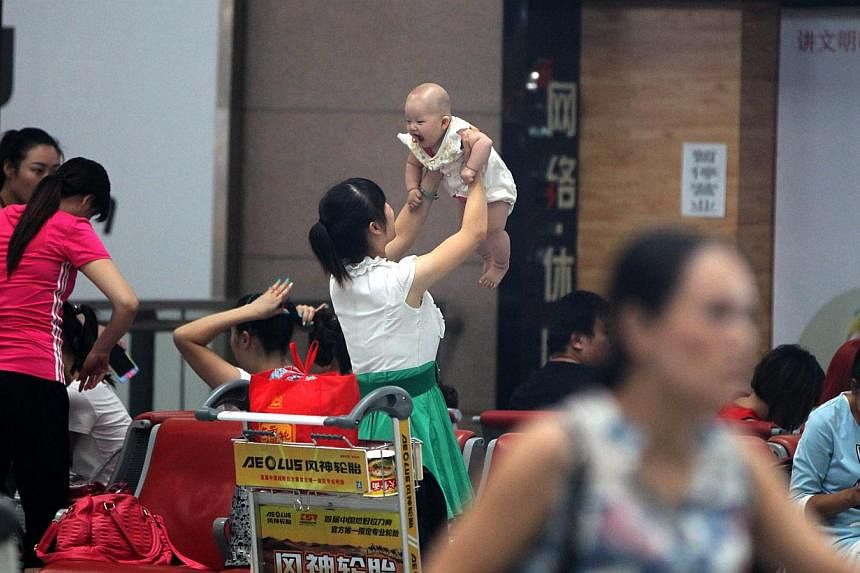 File picture of a woman holds her baby as she waits in Zhengzhou Xinzheng International Airport in Zhengzhou, central China's Henan province.&nbsp;China suffers from a huge gender imbalance as a result of sex-selective abortions and the strict family