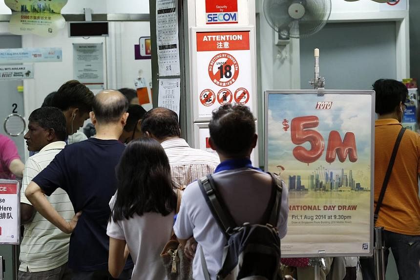 People queuing up at the Singapore Pools outlet along Toa Payoh Lorong 1 for the $5-million National Day Toto Draw on Aug 1, 2014. -- ST PHOTO: KEVIN LIM
