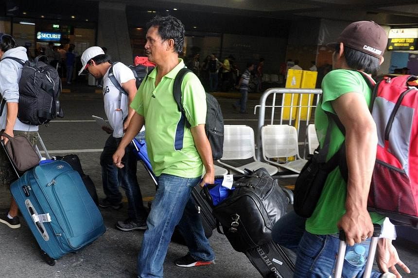 Filipino workers arrive at Ninoy Aquino International Airport in Manila on Aug 2, 2014, after leaving strife-torn Libya at government expense. -- PHOTO: AFP