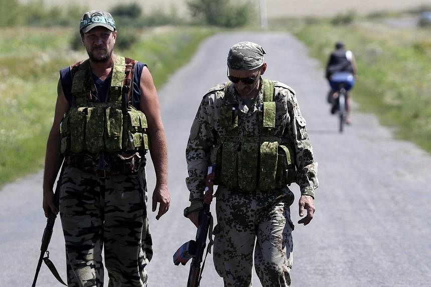 Armed pro-Russian separatists walk near the site where the downed Malaysia Airlines flight MH17 crashed, near the village of Hrabove (Grabovo) in Donetsk region, eastern Ukraine on Aug 1, 2014.&nbsp;Shelling close to the vast crash site of downed fli