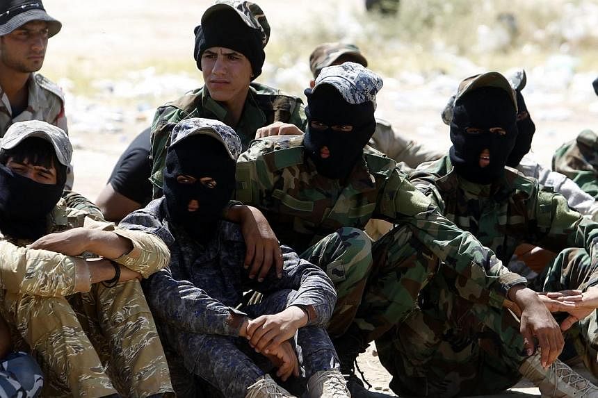 Shi'ite volunteers, who have joined the Iraqi army to fight against militants of the Islamic State, formerly known as the Islamic State of Iraq and the Levant (ISIL), sit together during training in Baghdad, July 9, 2014. -- PHOTO: REUTERS