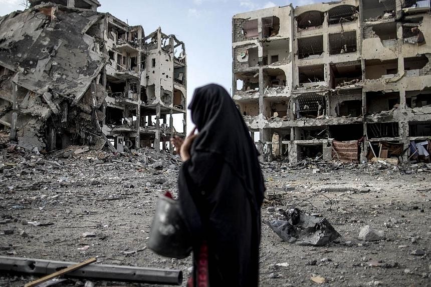 A Palestinian woman walks past destroyed buildings in Beit Lahia in the northern Gaza Strip on Aug 3, 2014 as the Israeli-Hamas conflict enters its 27th day in the besieged territory.&nbsp;Renewed Israeli shelling killed at least 30 people in Gaza on