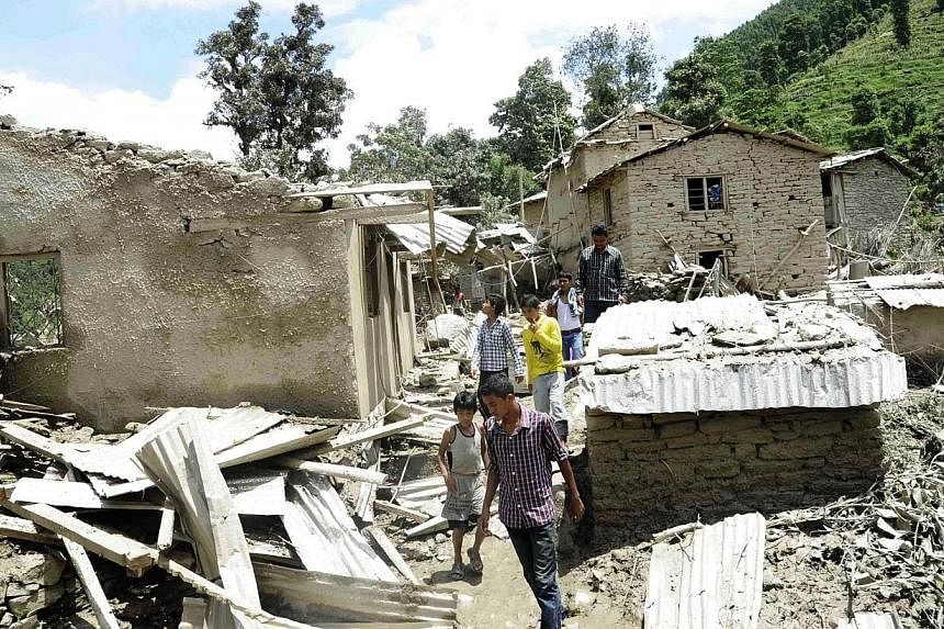 In this photograph released by the Nepalese Army on Aug 2, 2014, Nepalese residents stand near damaged houses after flooding near the scene of a landslide near the Sunkoshi River northeast of Kathmandu.&nbsp;Rescuers on Sunday, Aug 3, ruled out findi