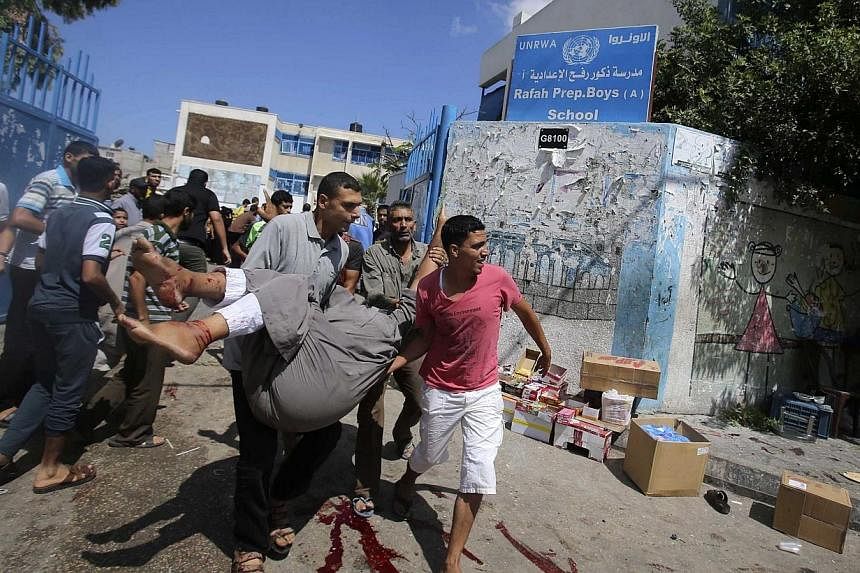 Palestinians carry a wounded man following what witnesses said was an Israeli air strike at a United Nations-run school, where displaced Palestinians take refuge, in Rafah in the southern Gaza Strip August 3, 2014.&nbsp;An Israeli air strike killed a