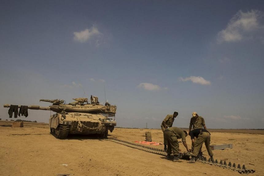 Israeli soldiers repair the track of a tank at a staging area outside the northern Gaza Strip July 29, 2014. Israel's military pounded targets in the Gaza Strip on Tuesday after Prime Minister Benjamin Netanyahu said his country should prepare for a 