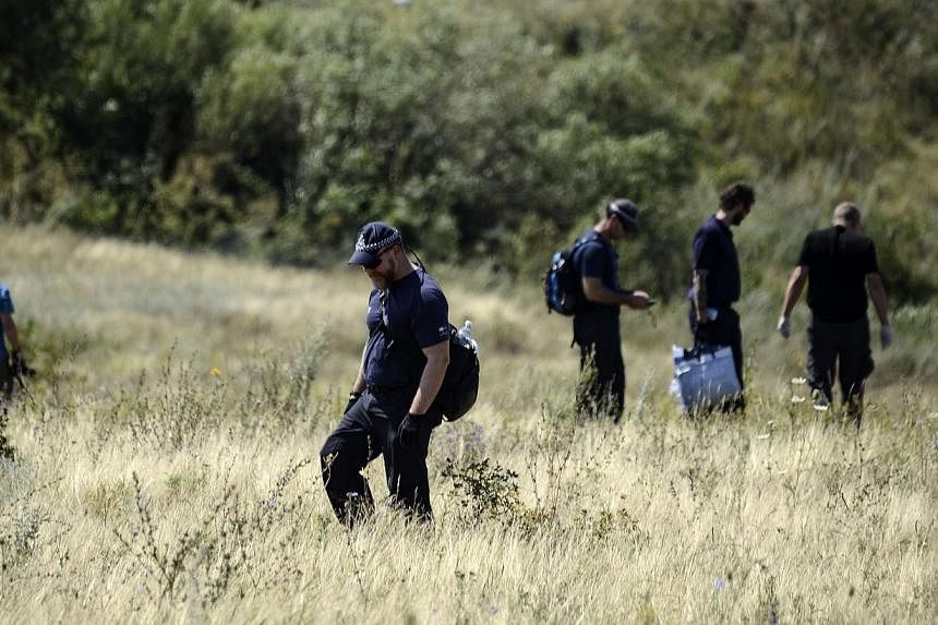 Dutch experts examine the area of the Malaysia Airlines Flight 17 plane crash in the village of Hrabove, Grabovo, some 80km east of Donetsk, on Aug 2, 2014. -- PHOTO: AFP&nbsp;