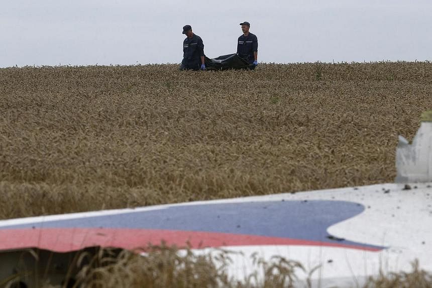 Members of the Ukrainian Emergency Ministry carry a body near the wreckage at the crash site of Malaysia Airlines Flight MH17, near the settlement of Grabovo in the Donetsk region in this July 19, 2014 file photo. &nbsp;-- PHOTO: REUTERS