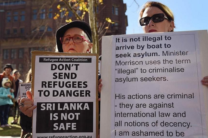 Two people hold placards at a rally protesting the Australian government's treatment of Sri Lankam asylum-seekers in Sydney on July 7, 2014.&nbsp;Asylum-seekers held on an Australian customs vessel at sea for weeks were given lifeboats and told to ma