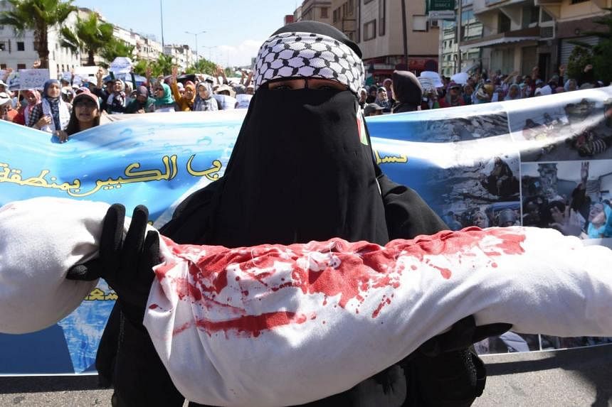 A Moroccan protester holds a fake body during a demonstration, against Israel's military campaign in Gaza, organised by the Islamic group Al Adl Wal Ihsane (Justice and Spirituality) in Casablanca on August 3, 2014. At least 10 people died in a fresh