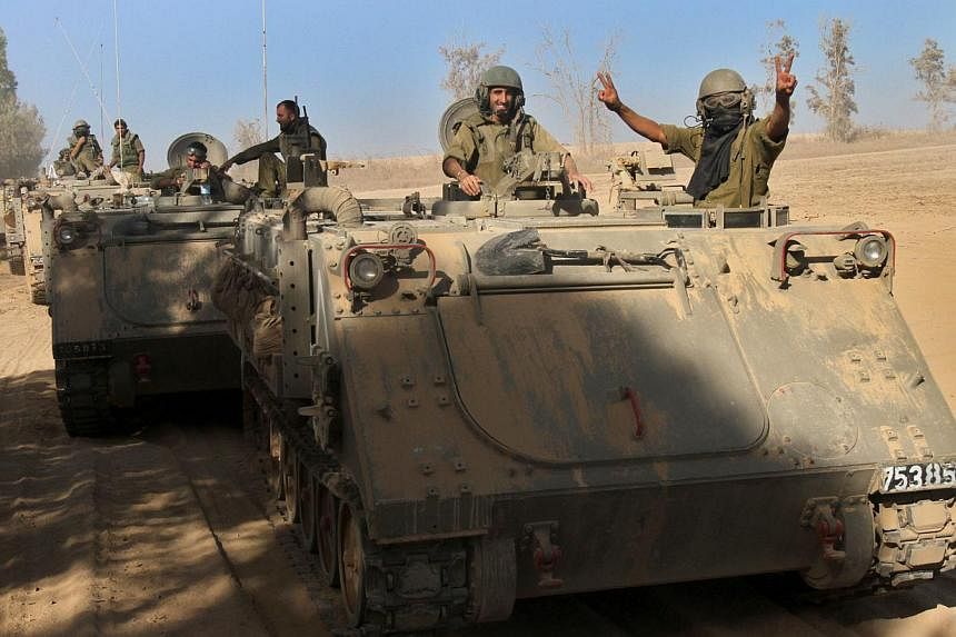 Israeli soldiers celebrate from their armoured personnel carriers (APC) along the border between Israel and the Gaza Strip after they pulled out from the Gaza Strip on Aug 3, 2014. &nbsp;-- PHOTO: AFP