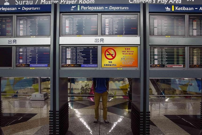 A man stand near flight information boards at Kuala Lumpur International Airport (KLIA) outside Kuala Lumpur. The airport, along with other major entry points in Malaysia, are on full alert for possible Ebola cases. -- PHOTO: REUTERS&nbsp;