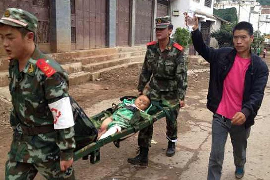 Rescuers carry an injuried child on a stretcher after a 6.1 magnitude earthquake hit the area in Ludian county in Zhaotong, south-west China's Yunnan province on August 3, 2014. The quake struck 11km west-northwest of the town of Wenping at a relativ