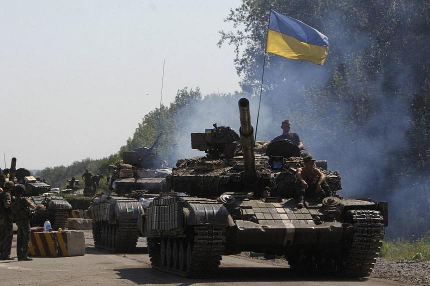 Ukrainian army tanks move past a checkpoint as they patrol the area near eastern Ukrainian town of Debaltseve on August 3, 2014. Nine civilians were killed in new fighting between government forces and pro-Russian separatists around the cities of Luh
