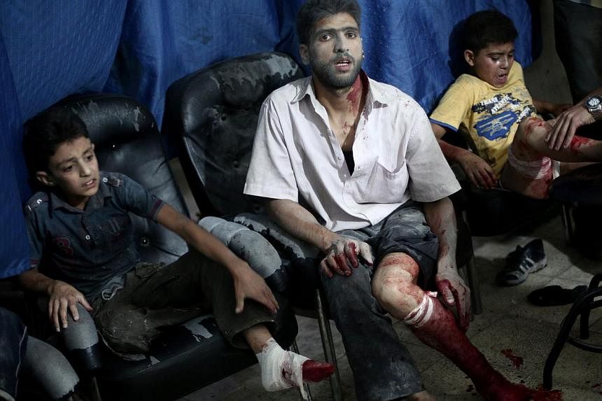Victims wait to be treated by medics at a makeshift hospital following reported shelling by Syrian government forces in Douma, north-east of Damascus, on August 3, 2014. At least 32 people were killed in Syrian regime air raids on two rebel-held town