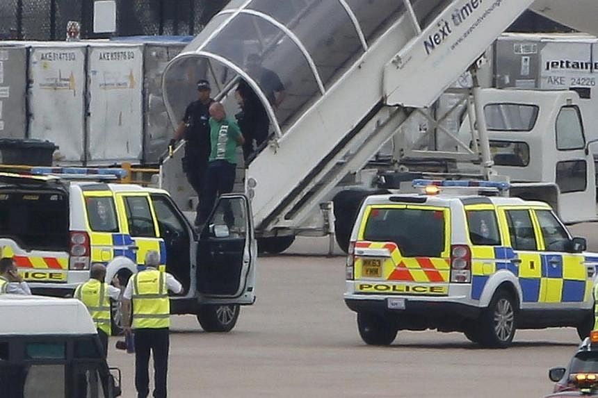 A handcuffed man is escorted off a Qatar Airways aircraft by police at Manchester airport in Manchester, northern England August 5, 2014. &nbsp;-- PHOTO: REUTERS
